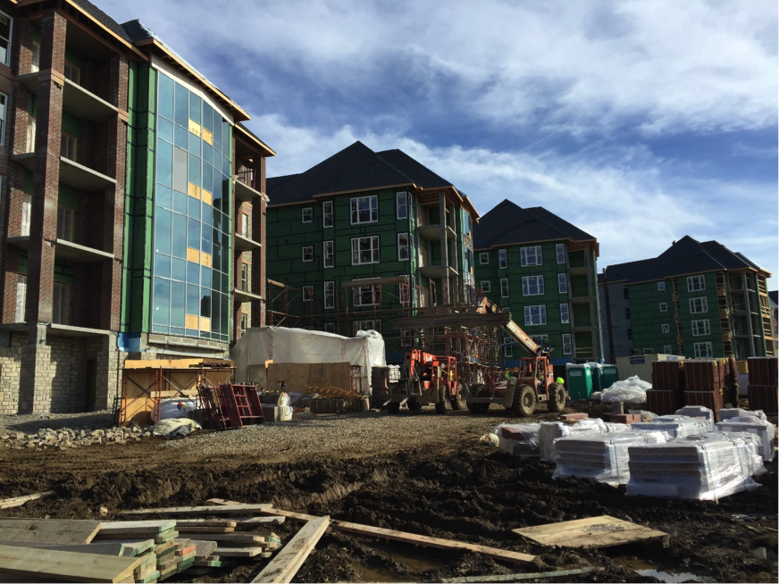 Buildings under construction with windows in place dirt ground with machines out front