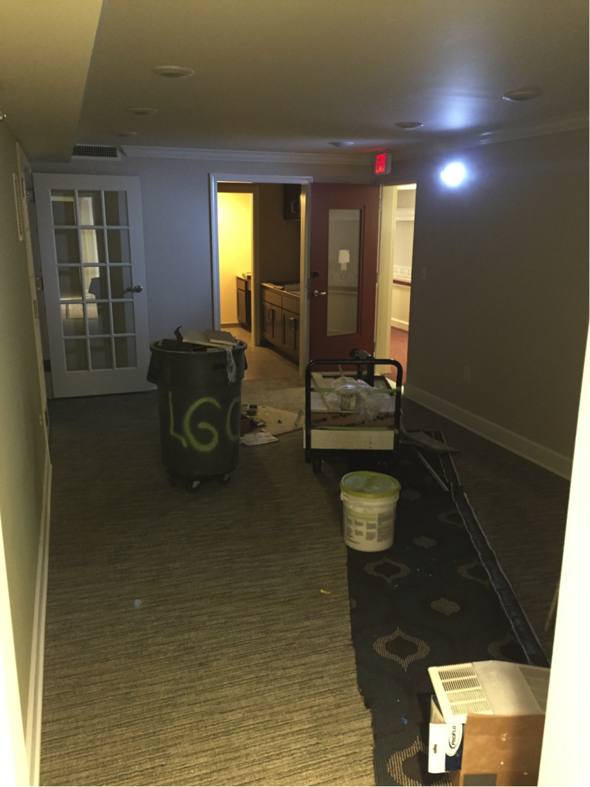 Office with carpet in place with tools and a trash can in the middle
