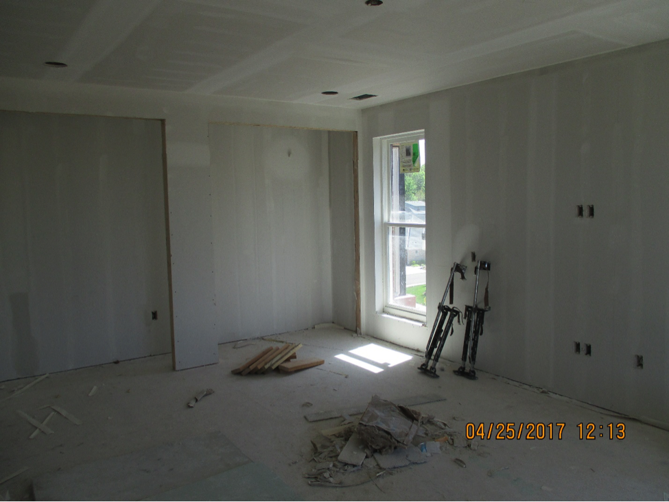 Room under construction with plastered walls and tools and wood on the ground