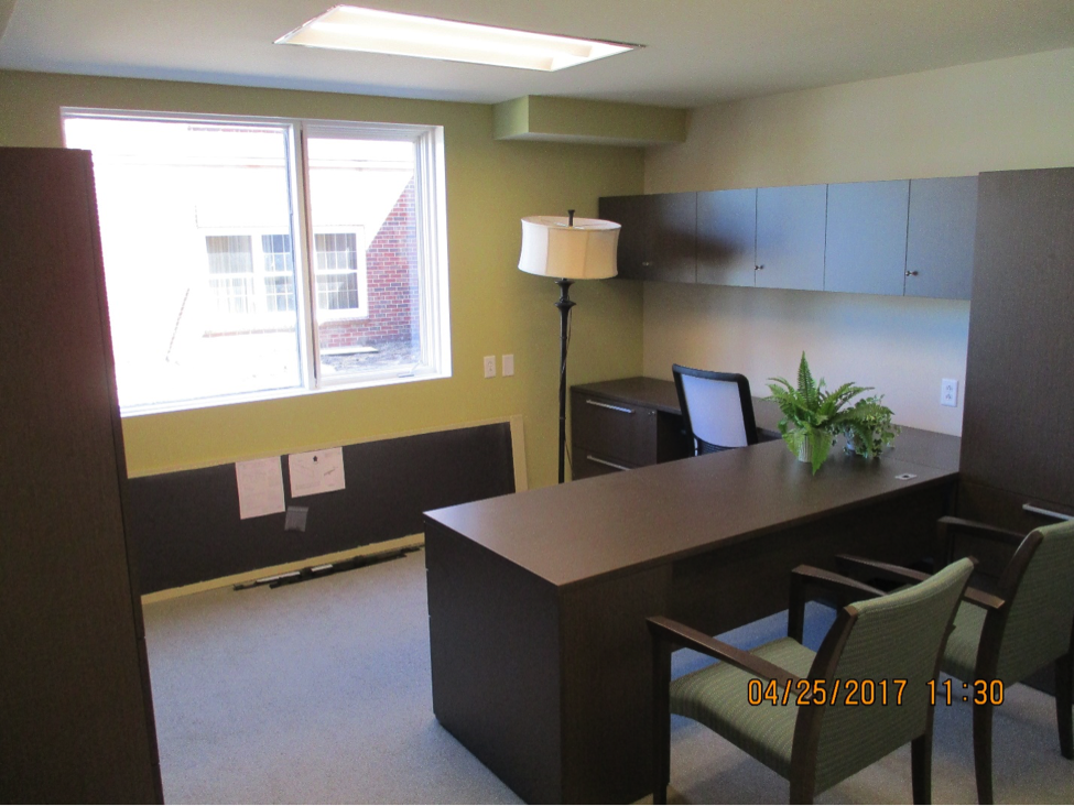 Office with a brown wood desk and light shinning through windows