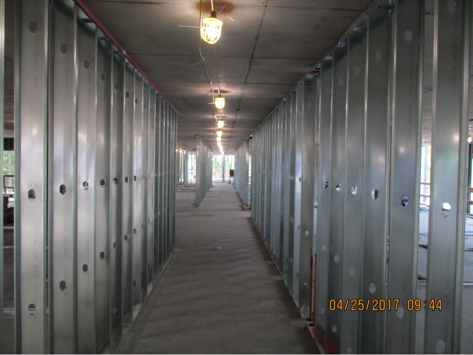 metal studded framing down a hall way with exposed lights on the celling