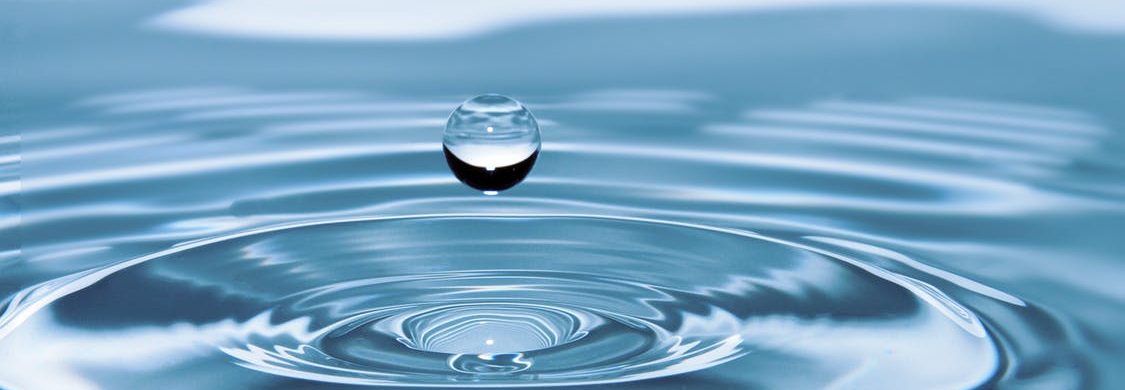 Drop of water falling into bigger puddle of water