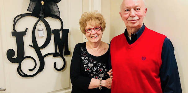 Couple standing in front of their front door smiling
