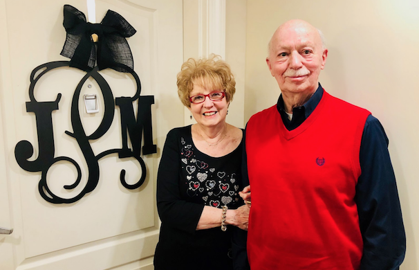 Couple standing in front of their front door smiling