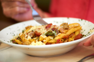 pasta in bowl with person eating it with a fork