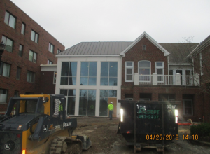 View of building with large glass windows and construction workers outside working