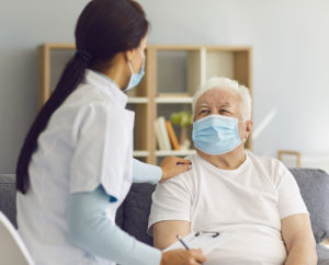 caregiver talks to senior man wearing mask