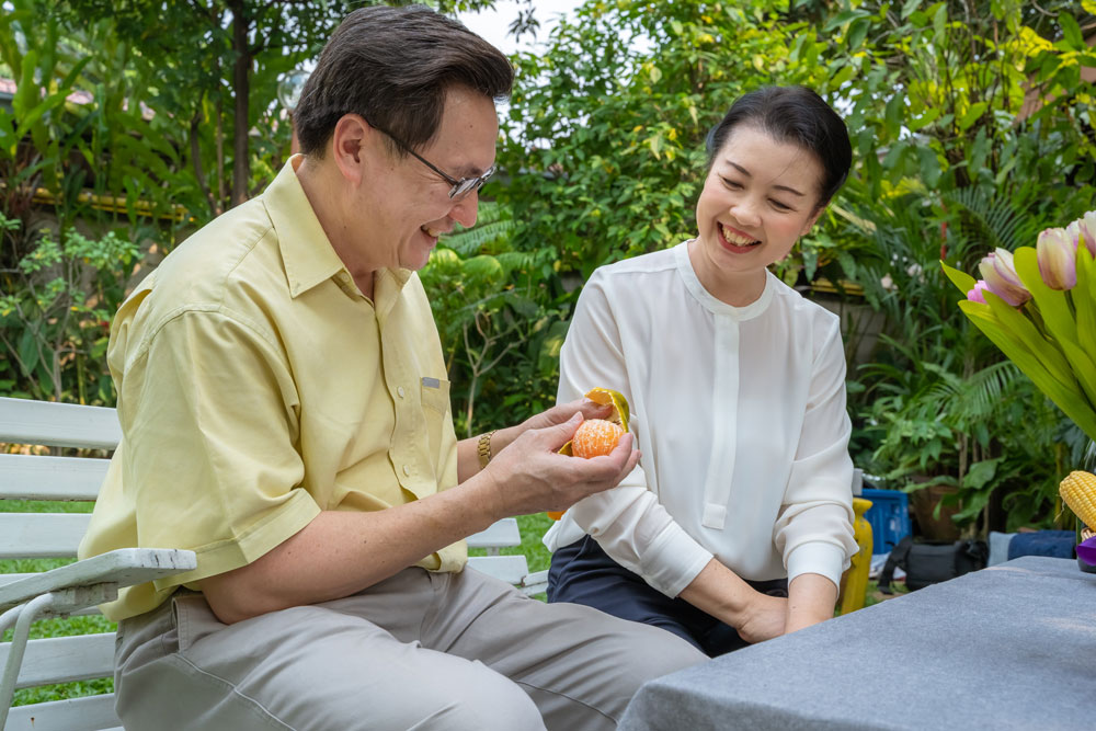 older asian couple eating oranges and talking about senior living