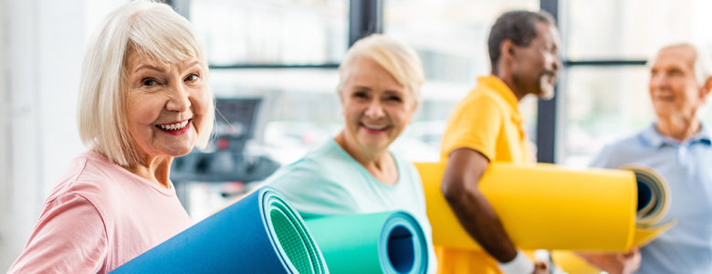 Group of seniors with exercise mats demonstrating physical wellness