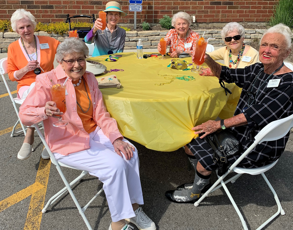 senior ladies raise their glasses while sitting at a round table