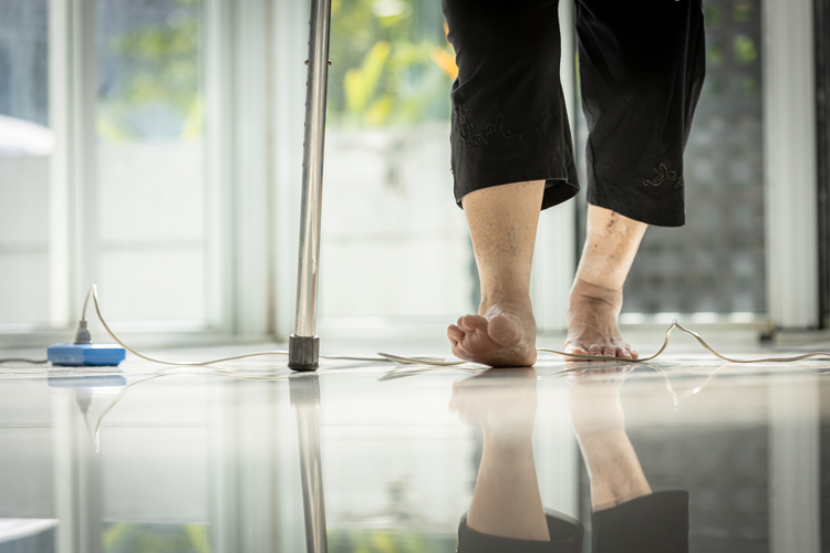 feet of olde woman about to trip over elecgtrical cord