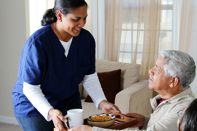 A caregiver serves a meal to a man in a Lifecare senior living community