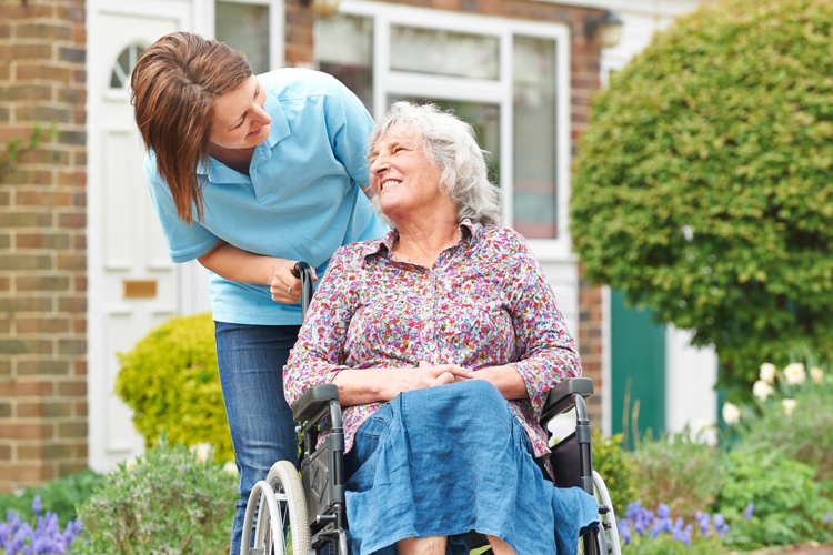 senior woman in wheelchair with carefiver in senior living community