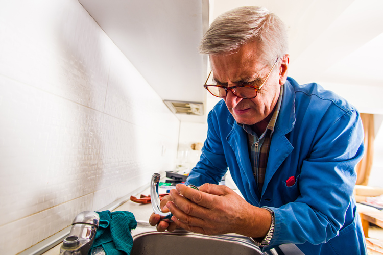Senior man fixing sink