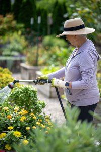 Resident waters flowers in her raised bed garden.