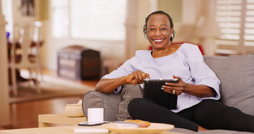 older african american woman relaxing on a couch with a tablet computer