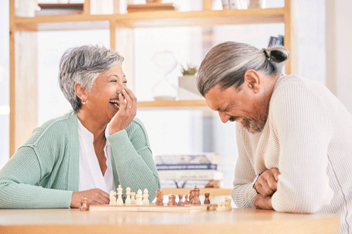 older couple laughing while playing chess
