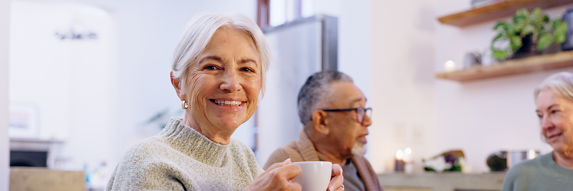 Senior woman with a coffee cup enjoying conversation with friends