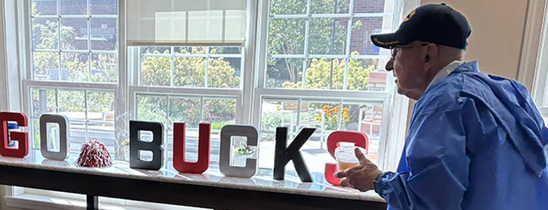 Man with Go Bucks sign in window