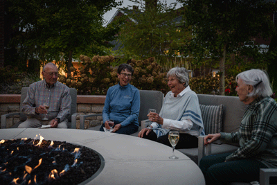 Residents enjoing drinks around a fire pit.