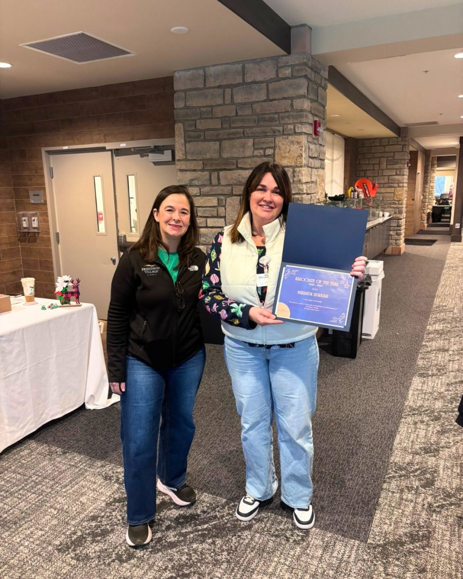 Director of Philanthropy, Betsy Gillespie, stands next to the 2025 FVD Associate of the Year, Miranda Hawkins, as she proudly displays her award framed in a blue presentation folder.