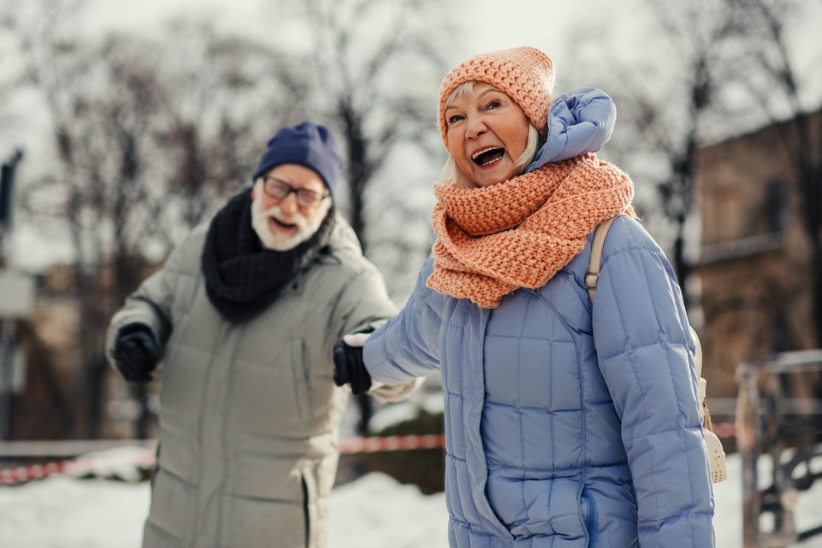 Older couple holding hands and laughing in the snow