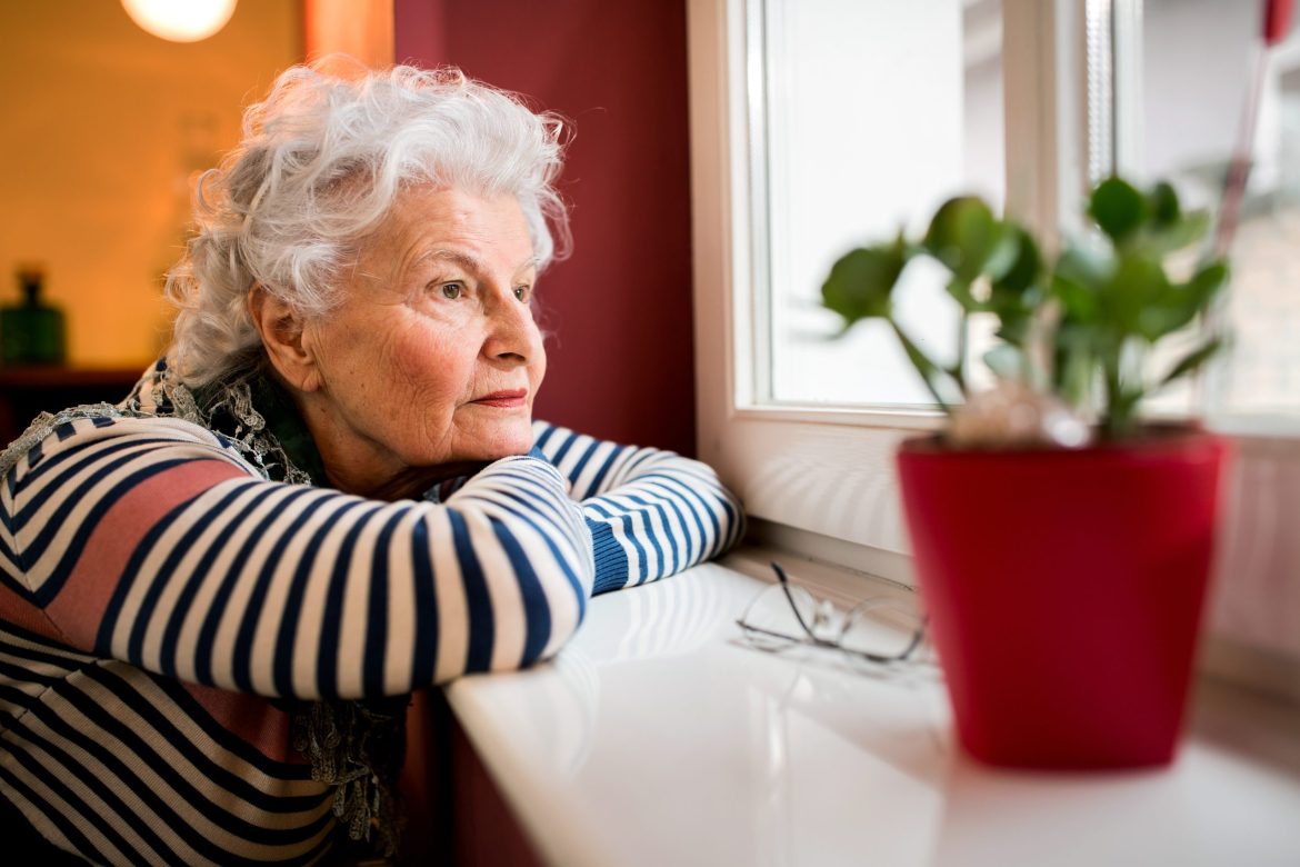 Lonely older woman staring out window