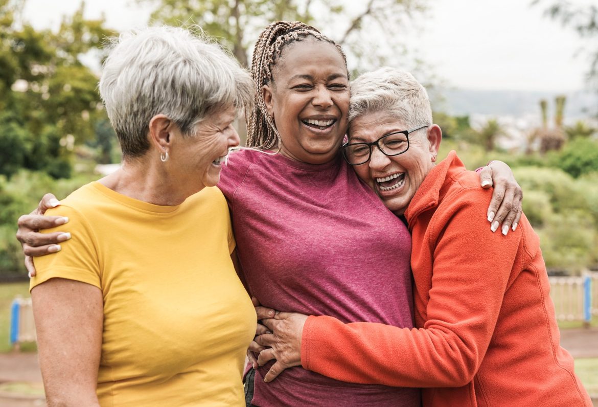 Vibrant older women smiling and embracing.
