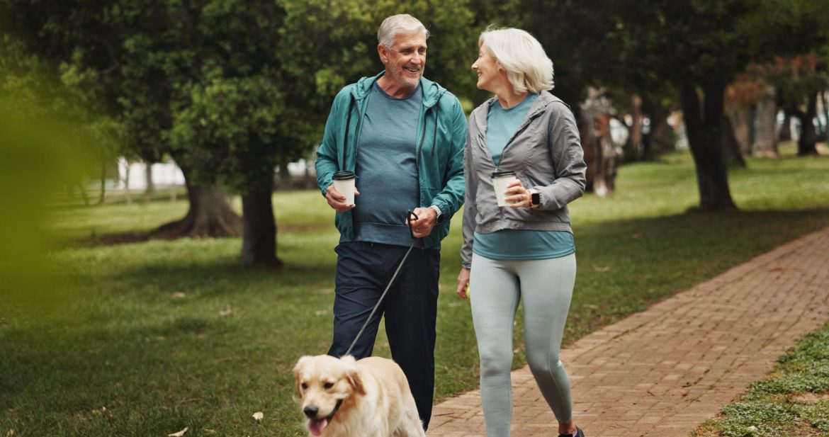 Older couple walking their dog in the park.