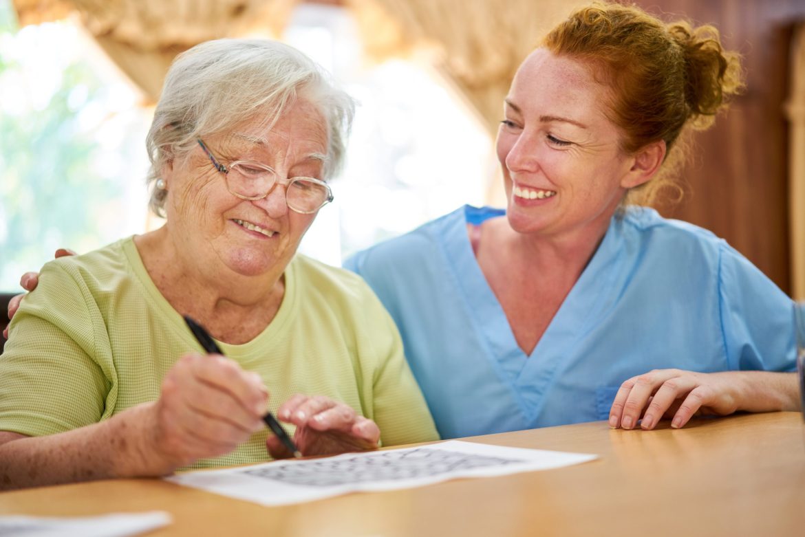 A staff member helps a Resident in memory care complete an activity.